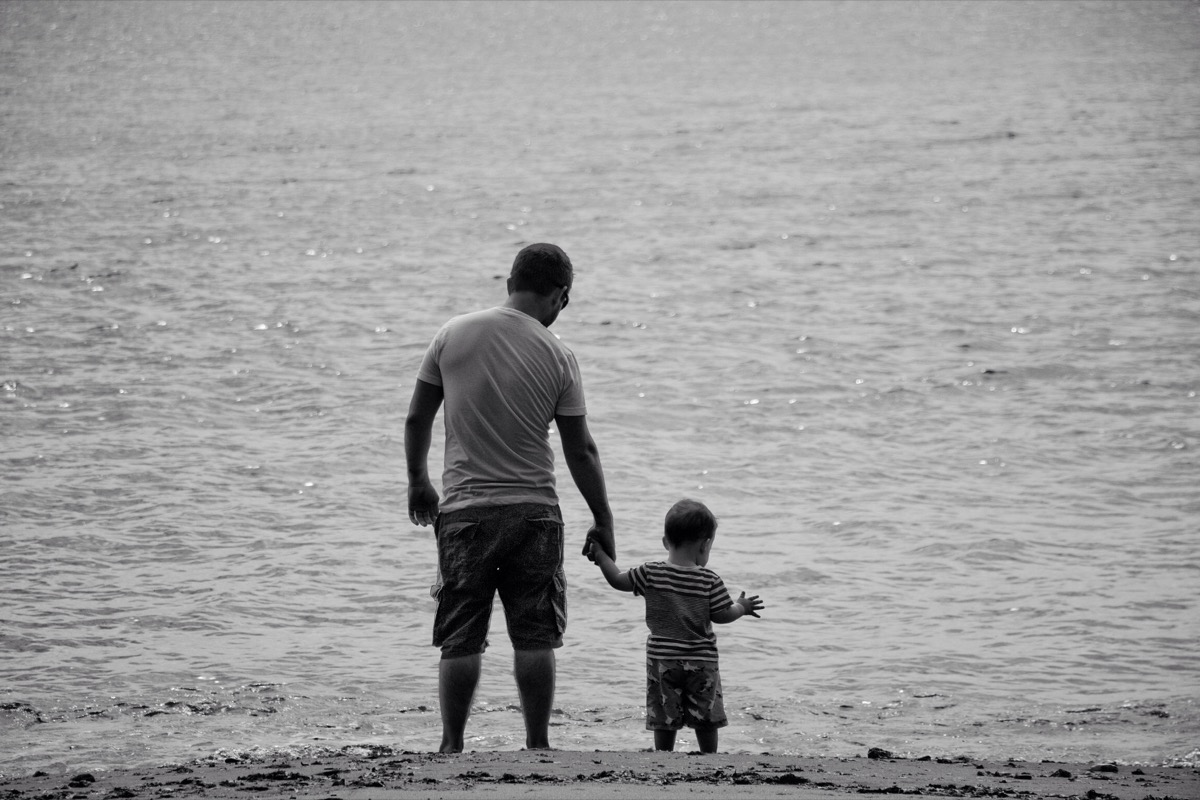 Pai com o bebé junto ao mar em momento de recolhimento e esperança